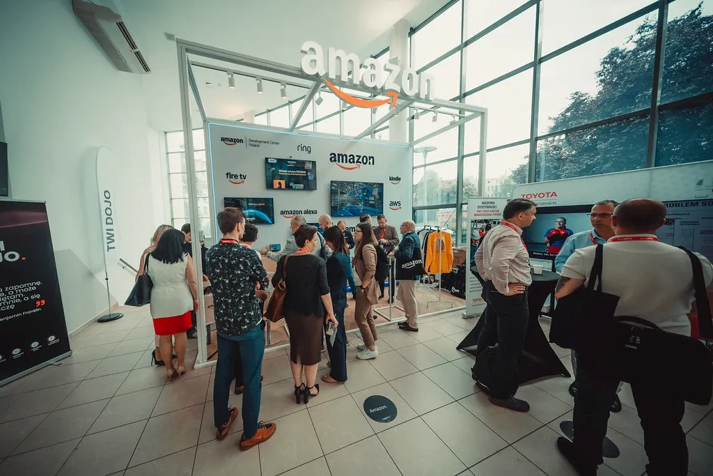 Amazon Polska trade show stand at the Lean TWI Summit, attendees exploring the stand