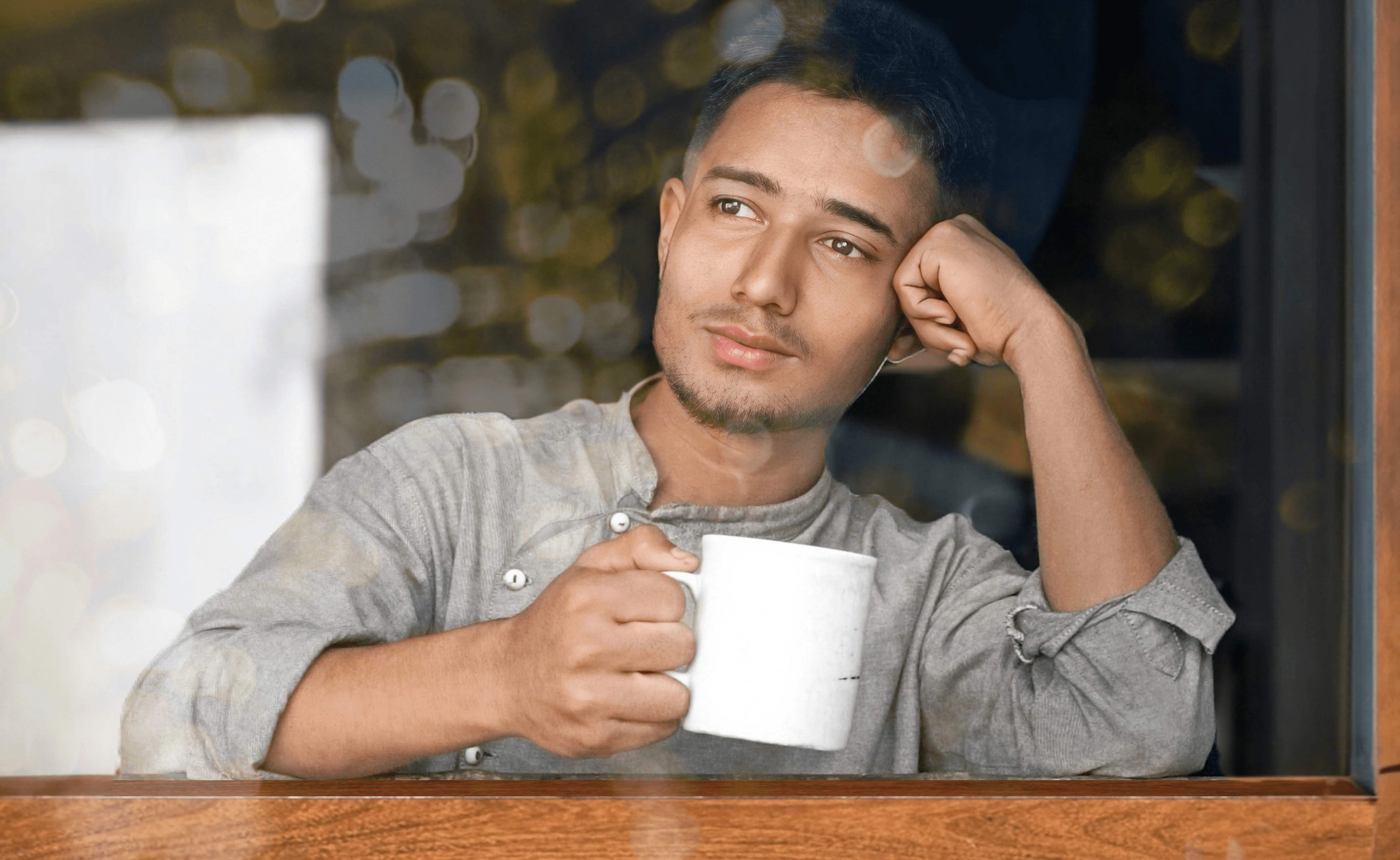 Man leaning on a counter with a cup of coffee