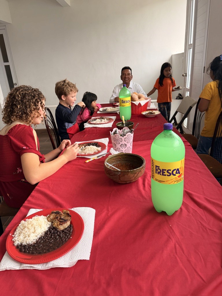 Children and adults sharing a meal around a long table.