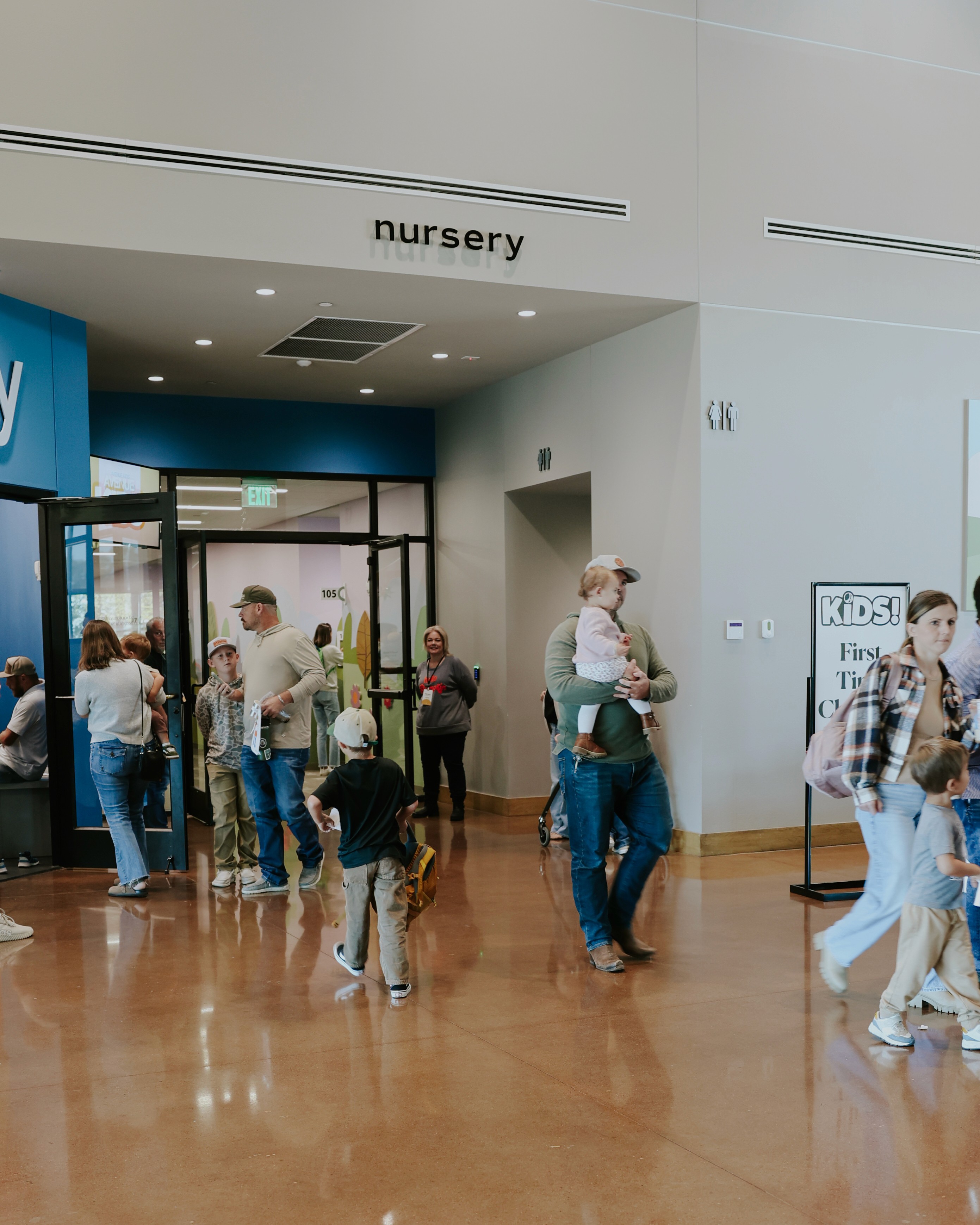 A busy market scene with people gathered, some cooking, and structures in the background under a bright sky.