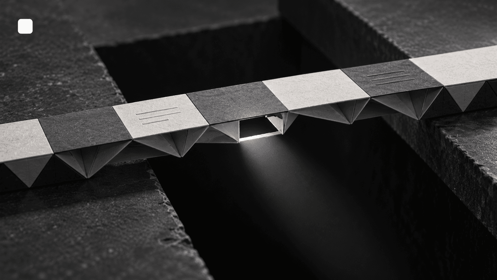 A folded-paper prototype bridge appears complete above a dark recess, while an inspection light reveals a missing connection beneath it. A small cubic icon sits at top-left.