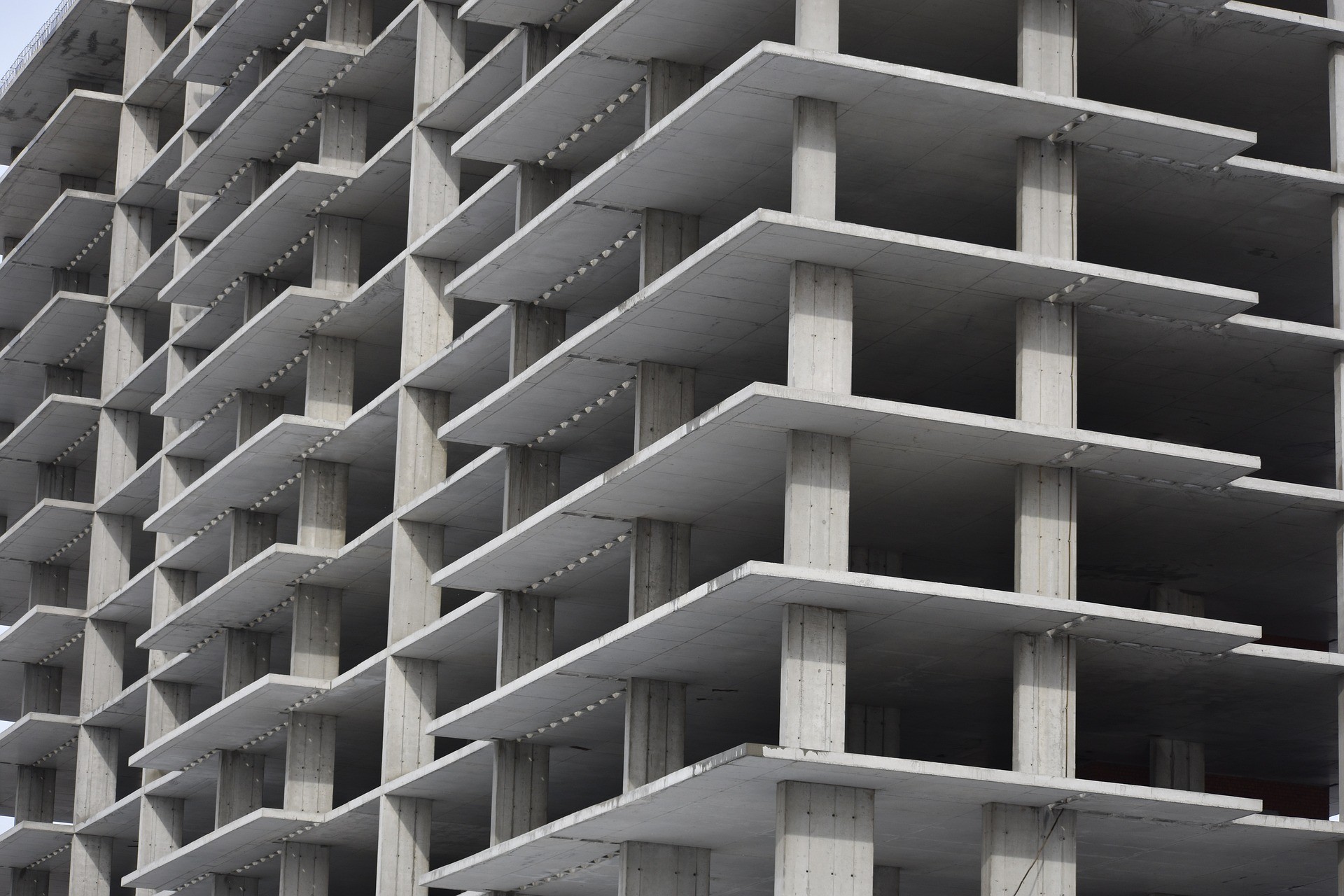 Estrutura de prédio em construção com concreto aparente, simbolizando obras, engenharia civil e construção imobiliária.