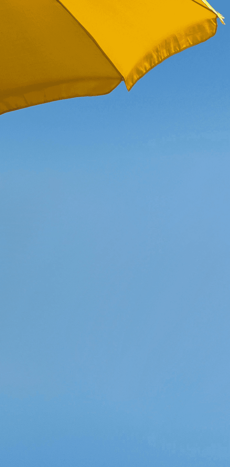 A bright yellow umbrella set against a clear blue sky, capturing a sunny and cheerful scene.