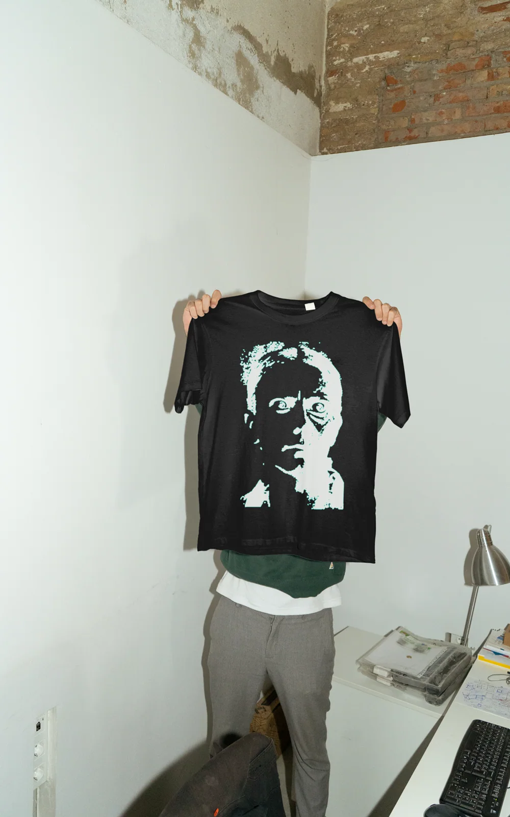 Portrait graphic T-shirt held up in a studio.