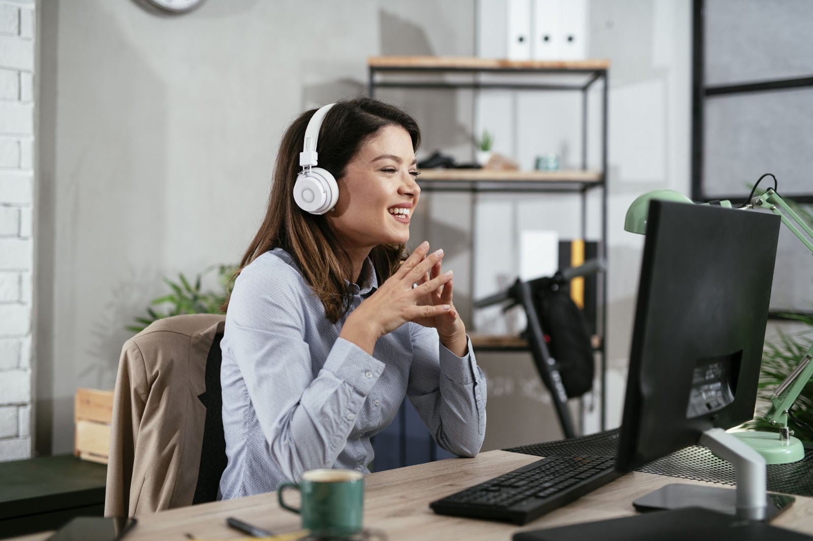 Smiling woman wearing headphones while in front of her computer