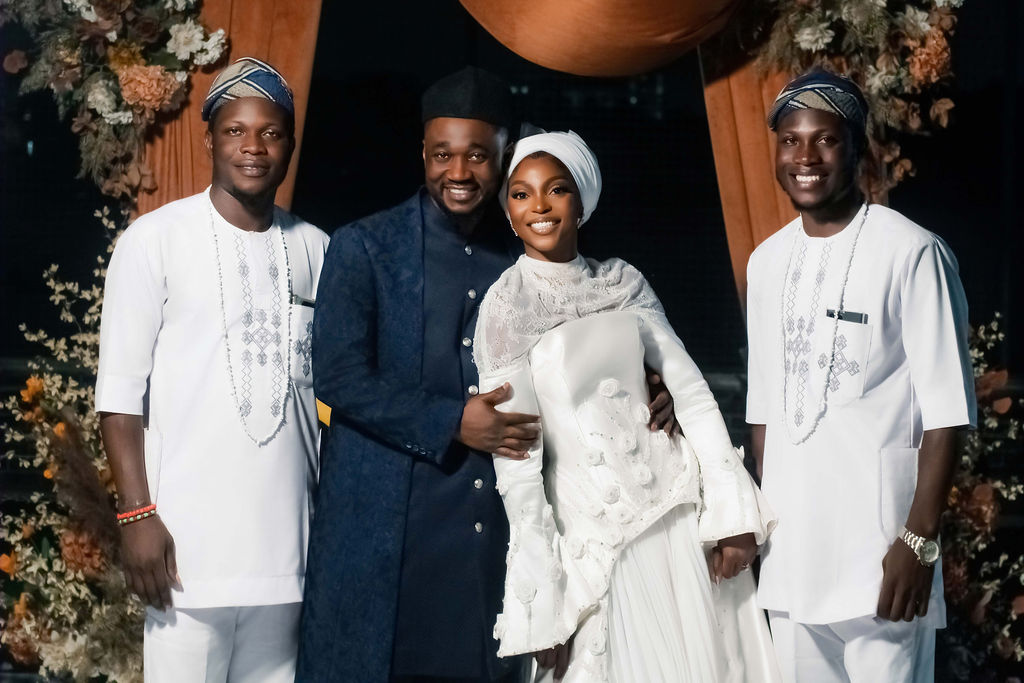 Luxury wedding planned by Victoria Brooks Events in Nigeria with elegant décor and beautiful reception. Groom in a blue suit and bride in a white wedding dress with flowers surrounded by family and friends.