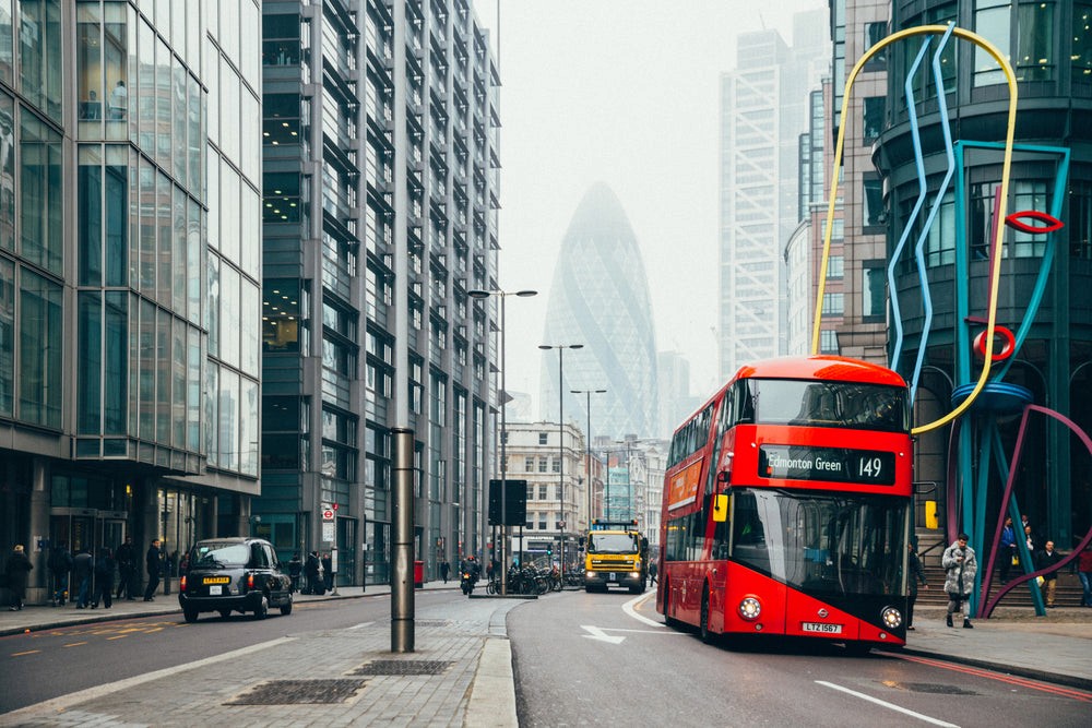 Londra'nın ikonik kırmızı otobüsleri ve modern şehir mimarisi altında vize rehberliği.