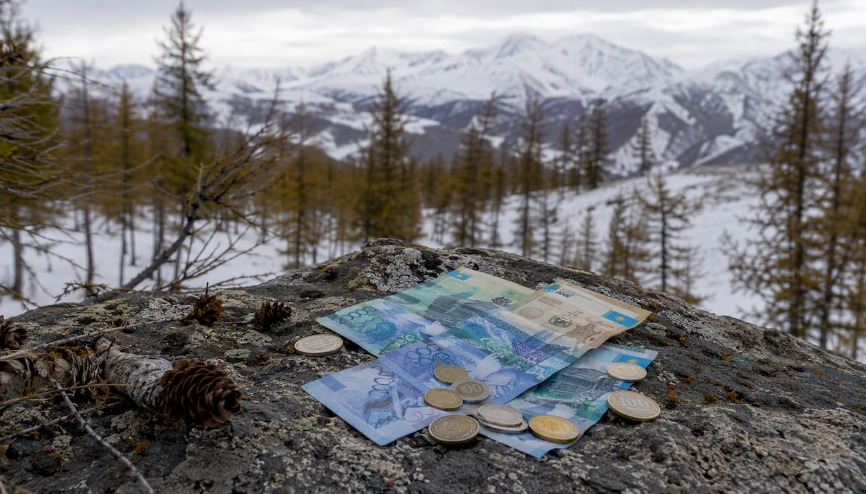Kazakhstani tenge banknotes and coins arranged on a wooden surface