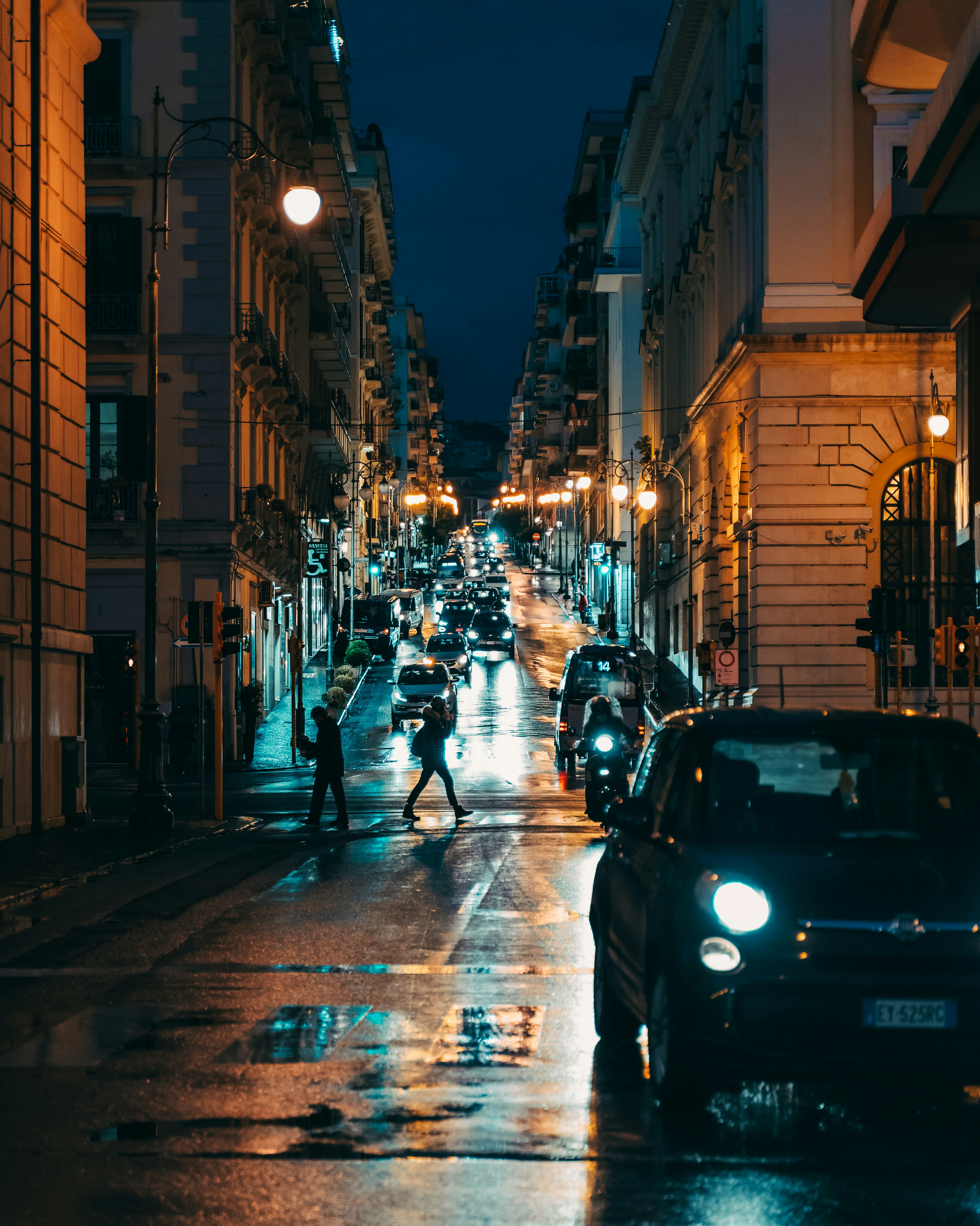 a couple of people crossing a street at night