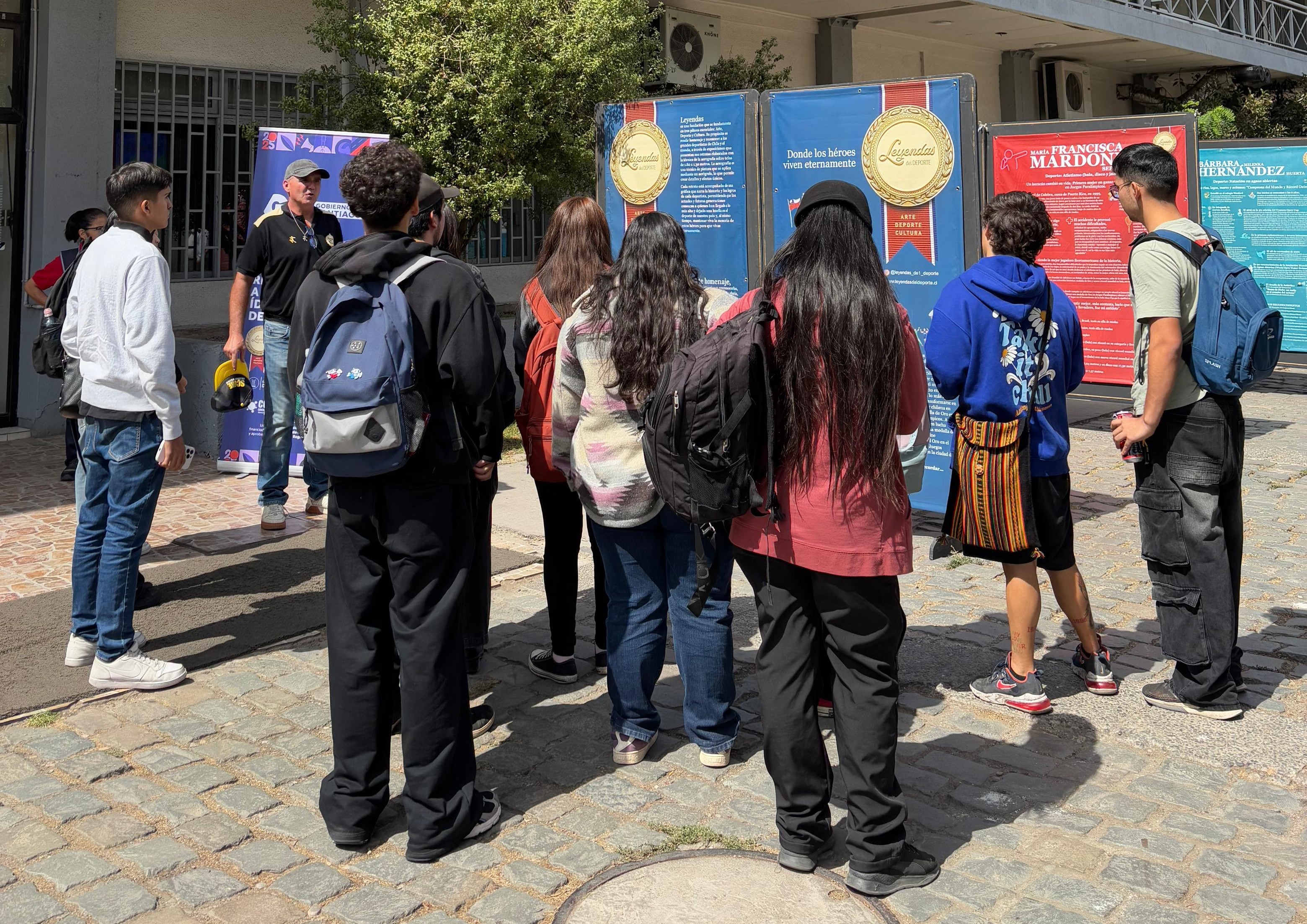 Visitantes en vista panorámica de la exposición de arte Leyendas del Deporte, admirando las pinturas de atletas chilenas.