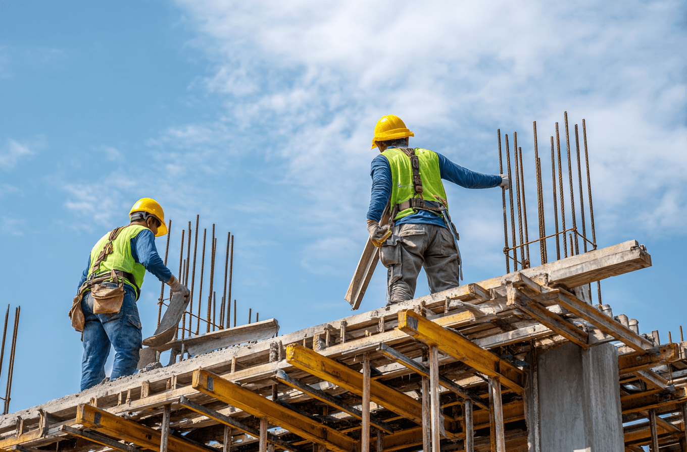 A woman in an orange sweater, wearing glasses, focused on coding at a computer screen.