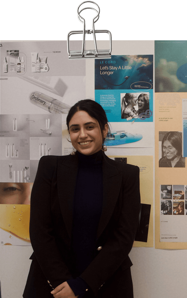 A model wearing an elegant cream blazer sits on a chair against a bright blue background, showcasing a modern and minimalist professional style.