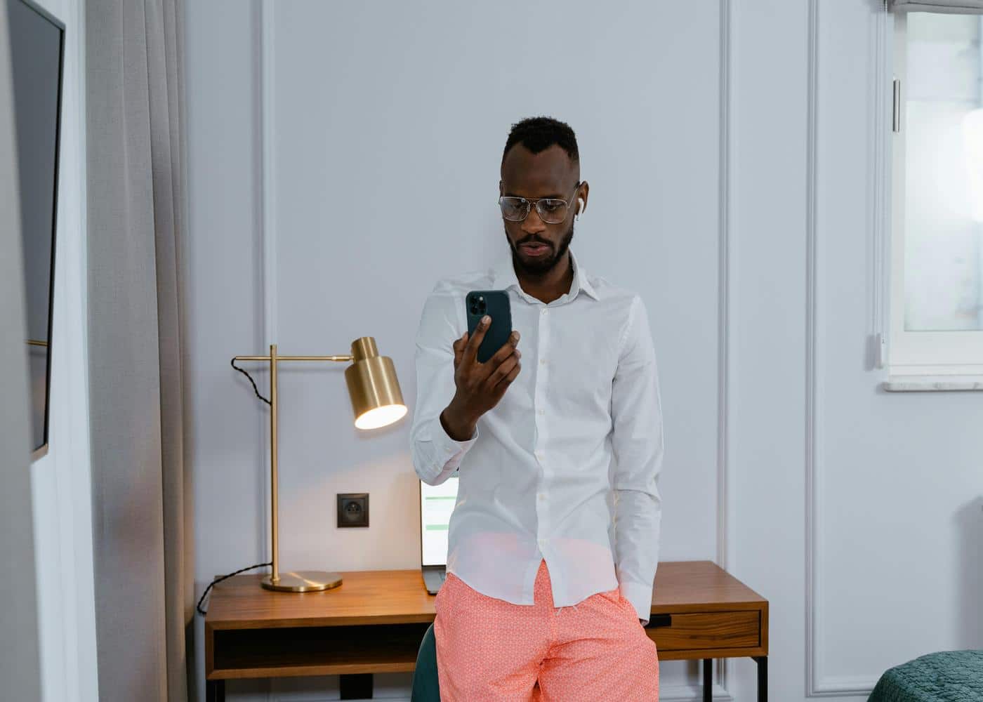 Man using a phone and leaning against a small desk
