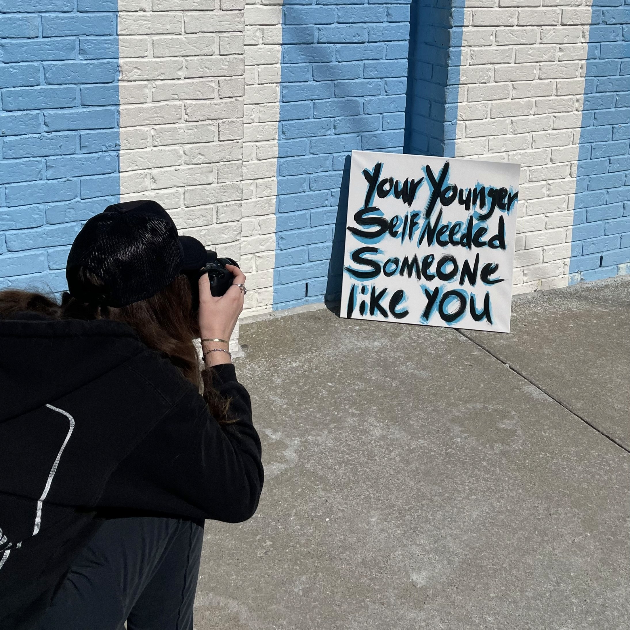 Abstract painting reading "your younger self needed someone like you"