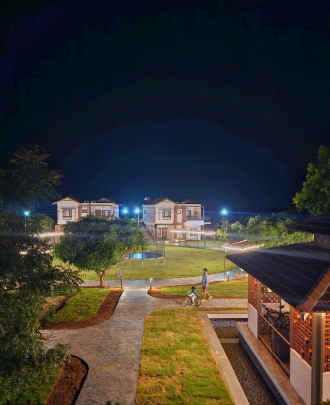 Cozy reading nook with sofa, chair, and plants inside a glass cabin with mountain forest views.