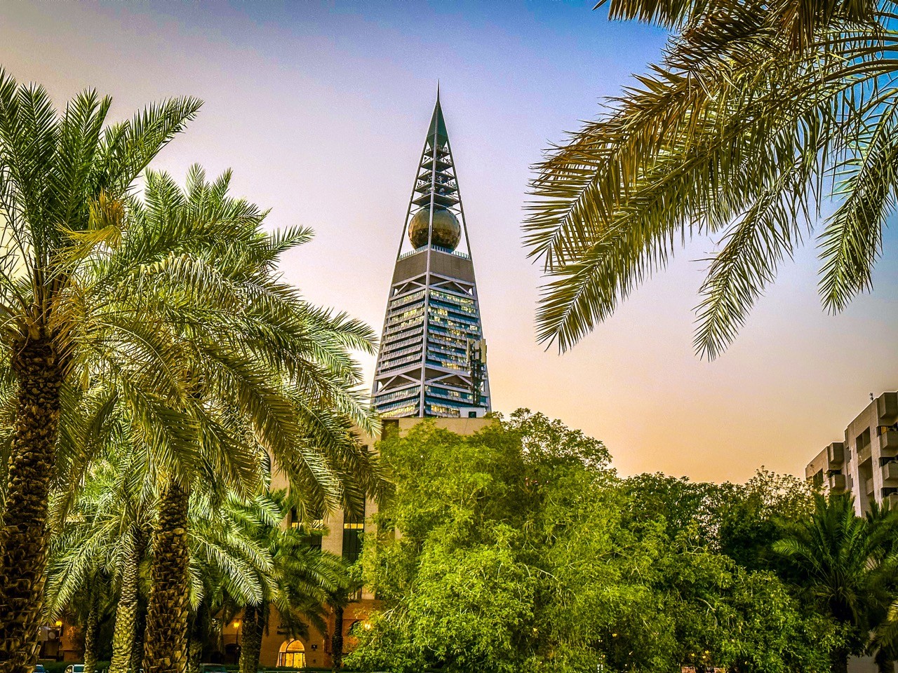 Al Faisaliah Tower rising above Riyadh, framed by palm trees, represents SAA Law’s dedication to guiding businesses through complex legal landscapes with strategic solutions.