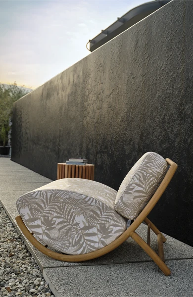 Luxury outdoor lounge setting featuring armchairs with solid Iroko wood frame and sculpted cushions, poolside in a modern villa with palm tree and designer side tables – elegant high-end furniture collection for refined outdoor living