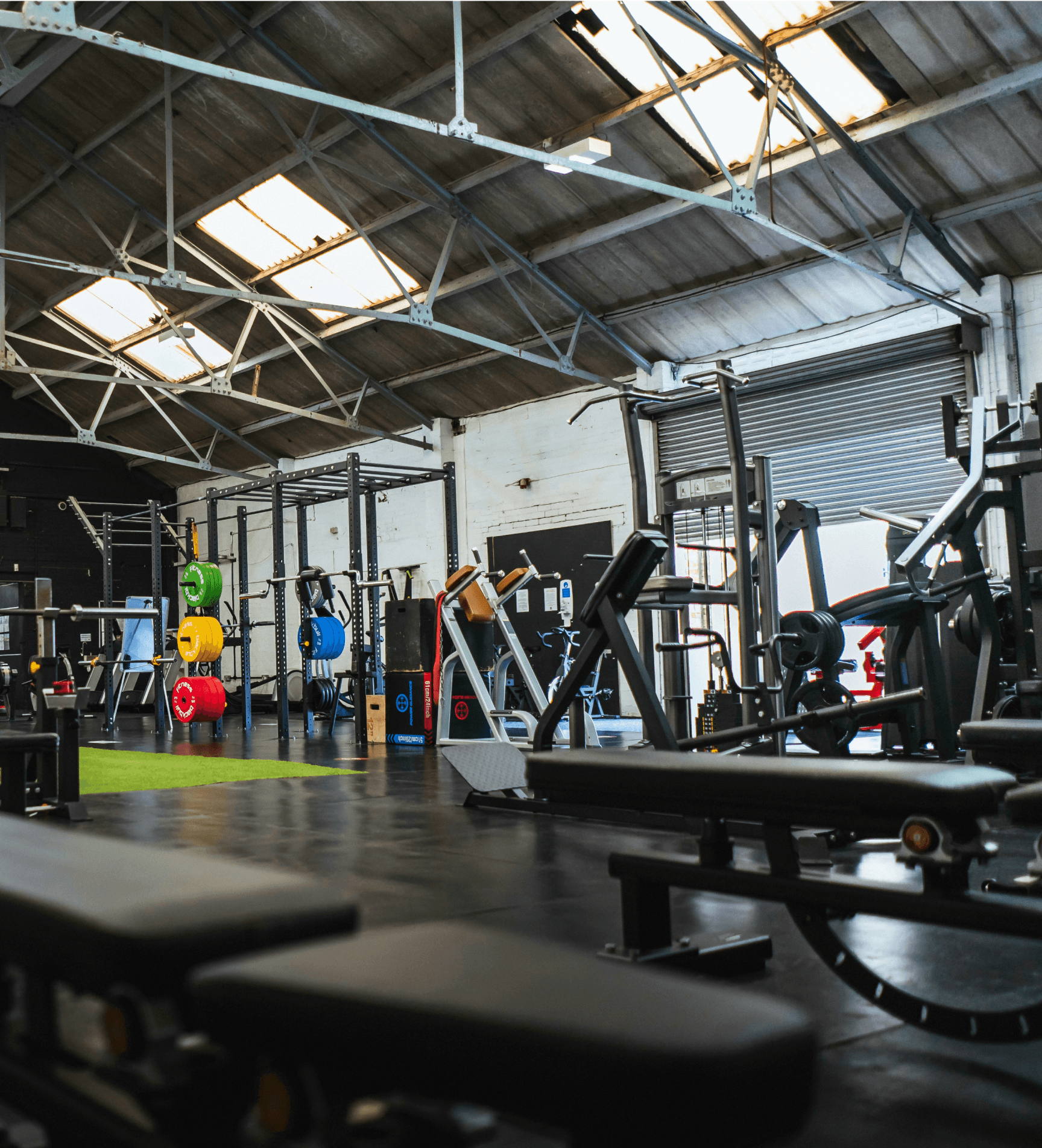 A spacious gym with various workout equipment, bright lighting, and a modern, industrial design.