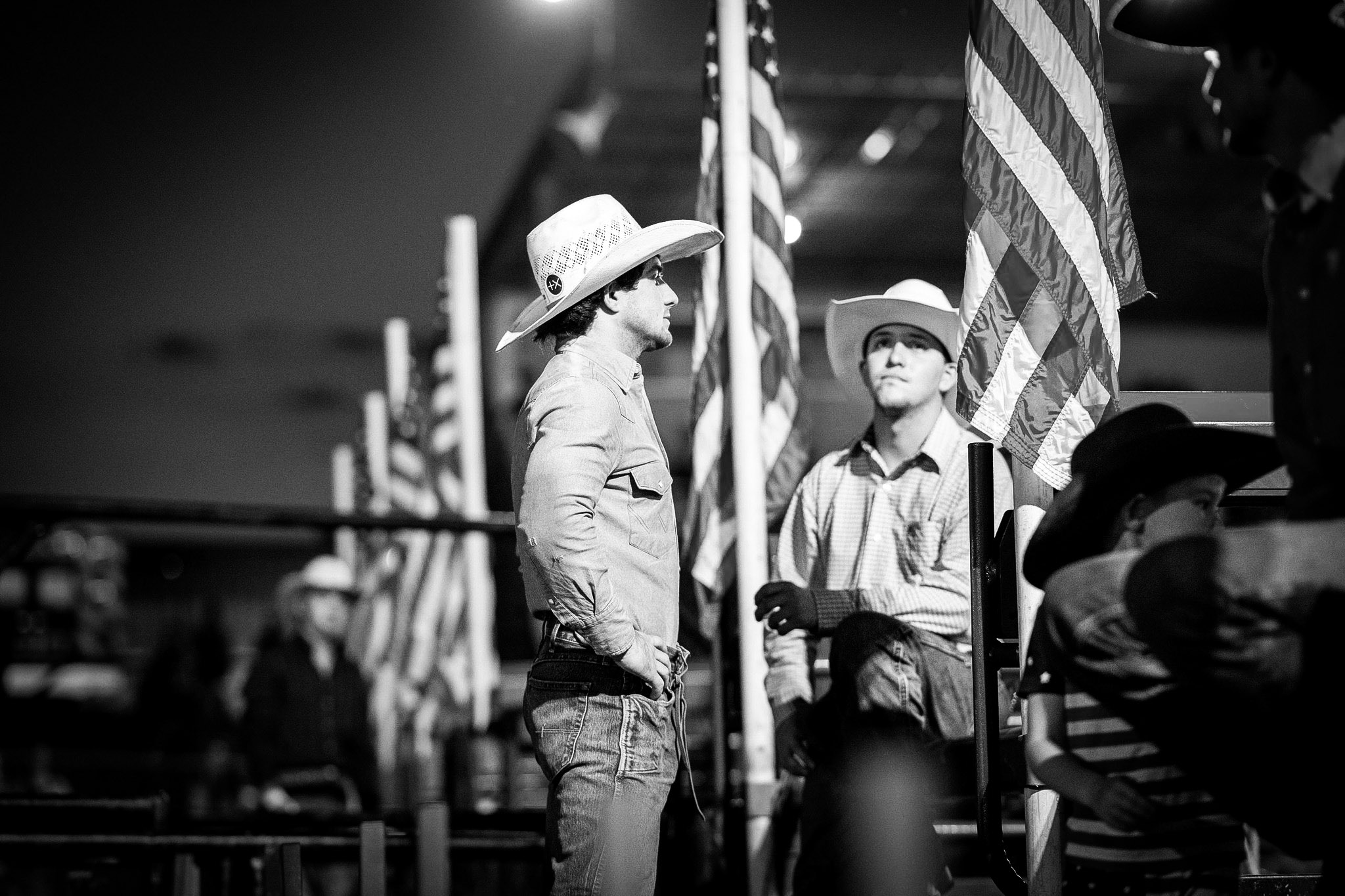 two cowboys near American flags at rodeo