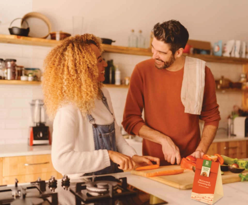 Younger couple cooking together, chopping vegetables.