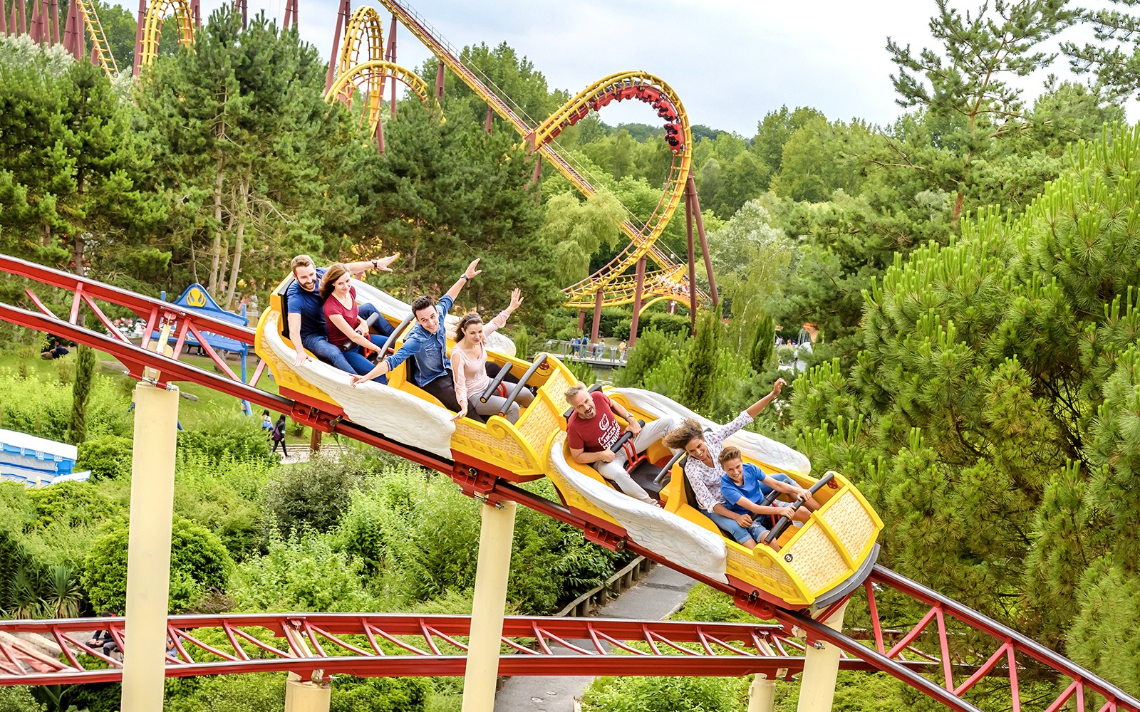 Visitors enjoying a roller coaster ride at Astérix Park, surrounded by lush greenery.