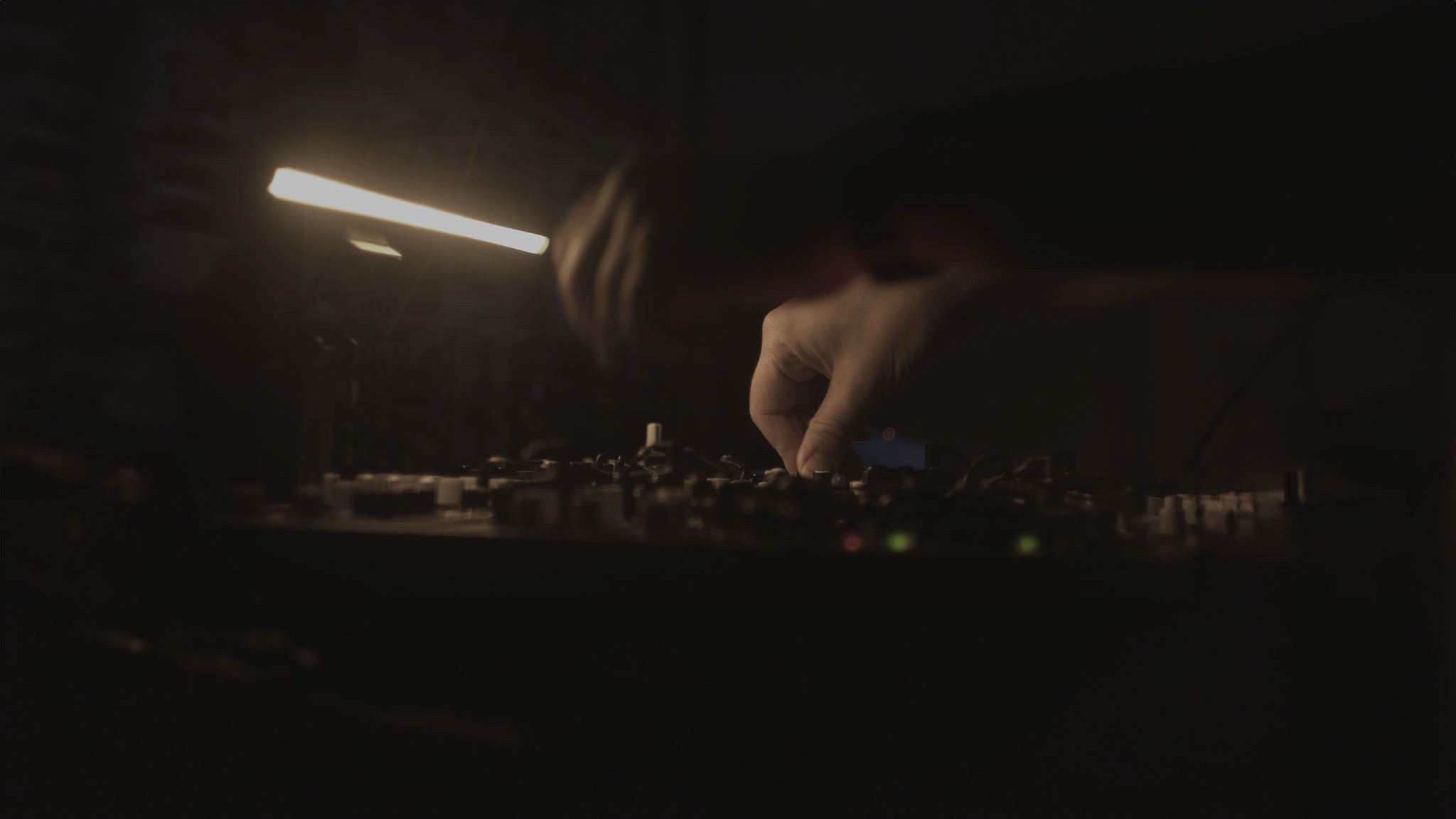 A film director sits in a chair facing a bustling, warmly lit night market scene. A camera setup is nearby, capturing the energetic atmosphere.