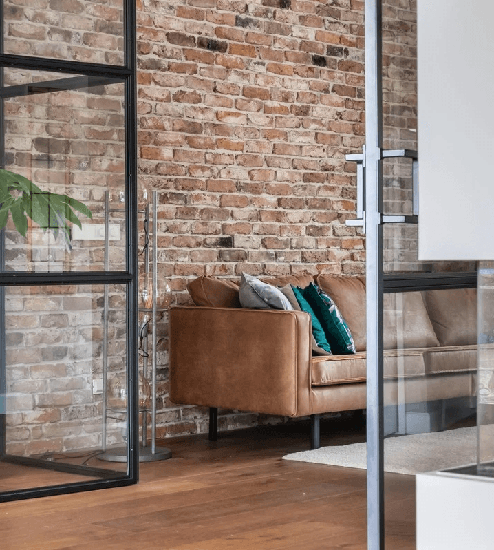 brick wall, steen muur met cognac leren bank en stalen deuren 