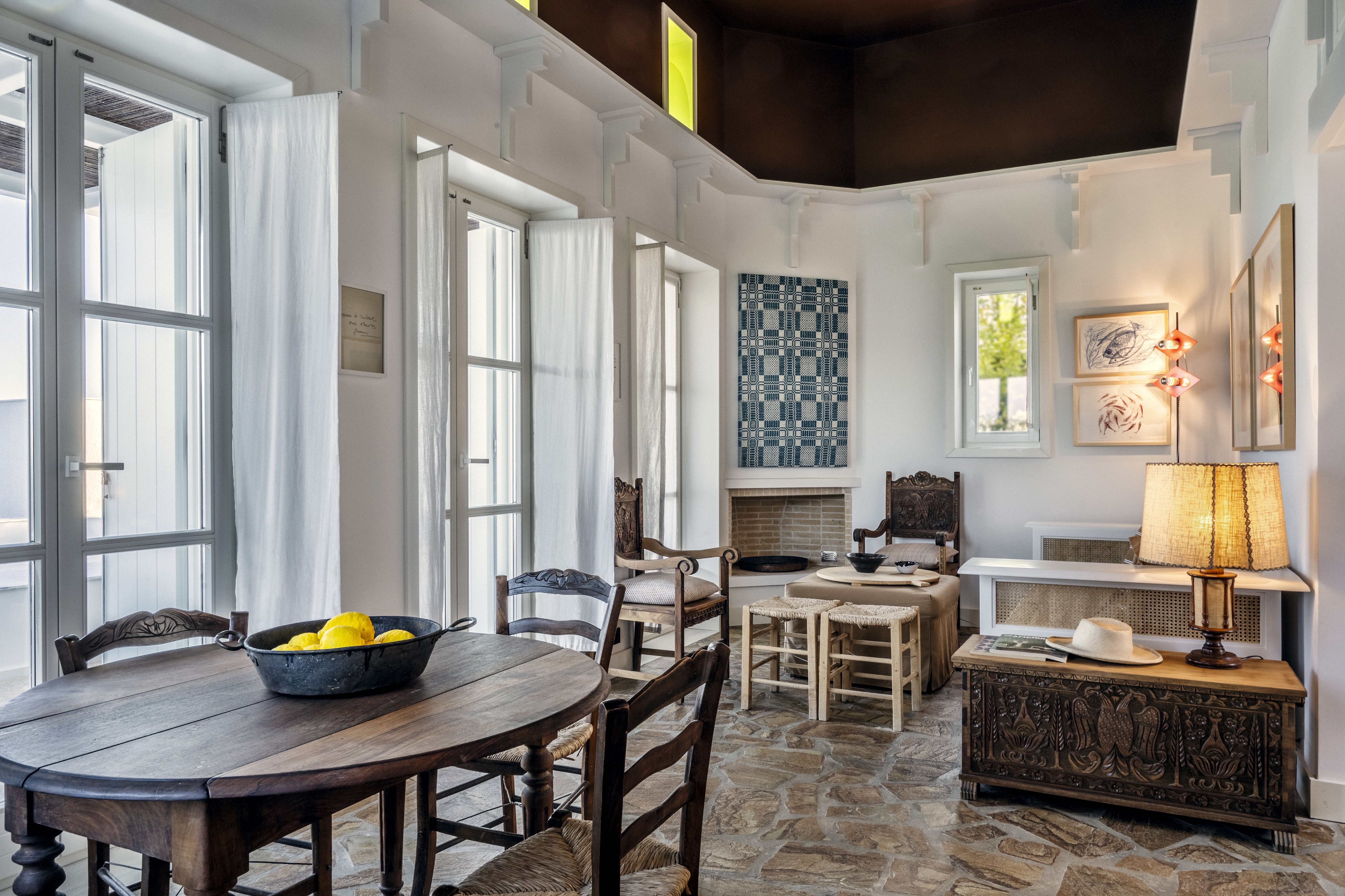 The living room of Rafter Koufonisia Galene featureing a wooden table, art, a fire place and a sofa.
