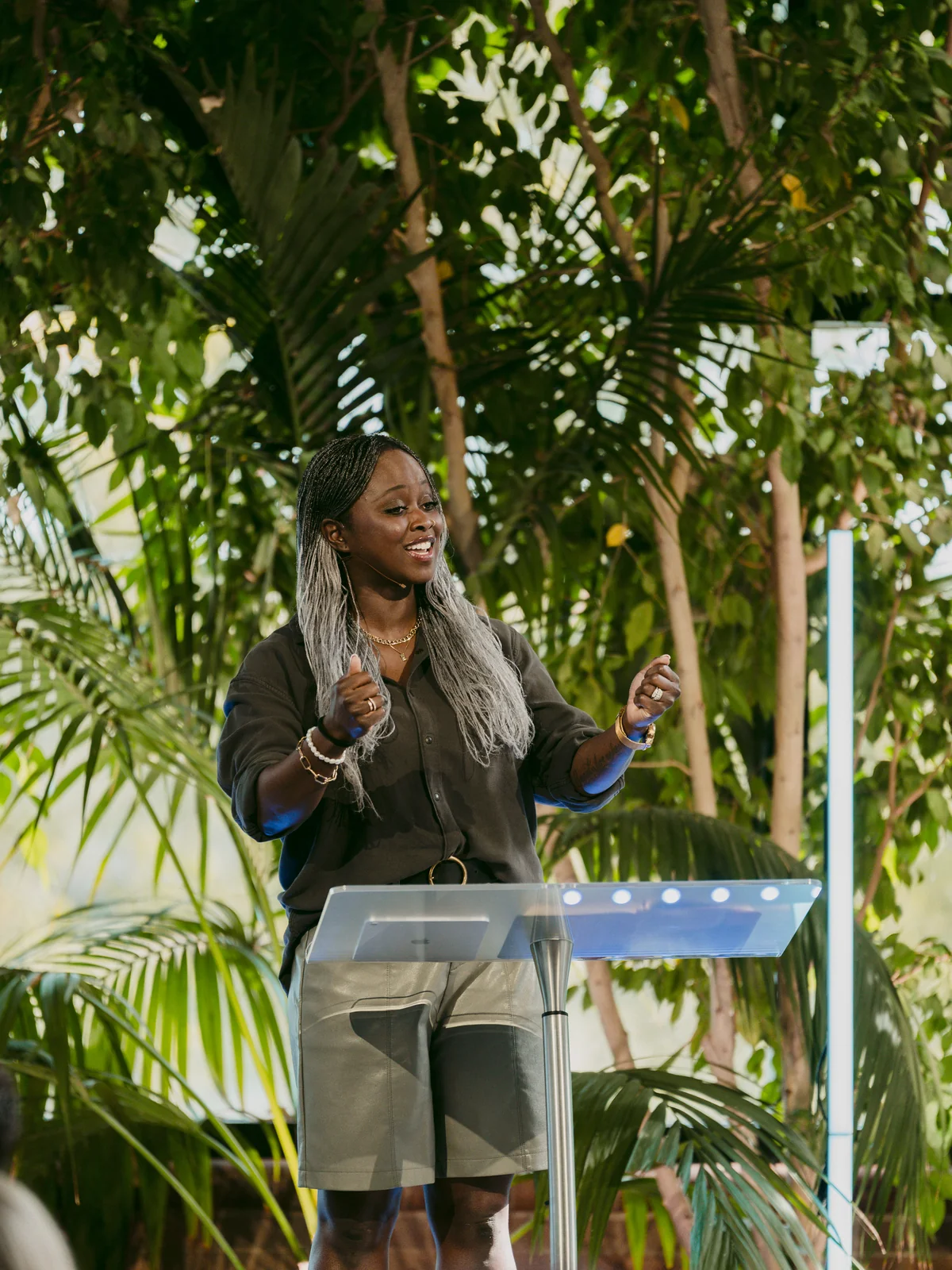 Pastor Juliet Lyons preaching from the stage surrounded by trees at Elan Church in Naperville