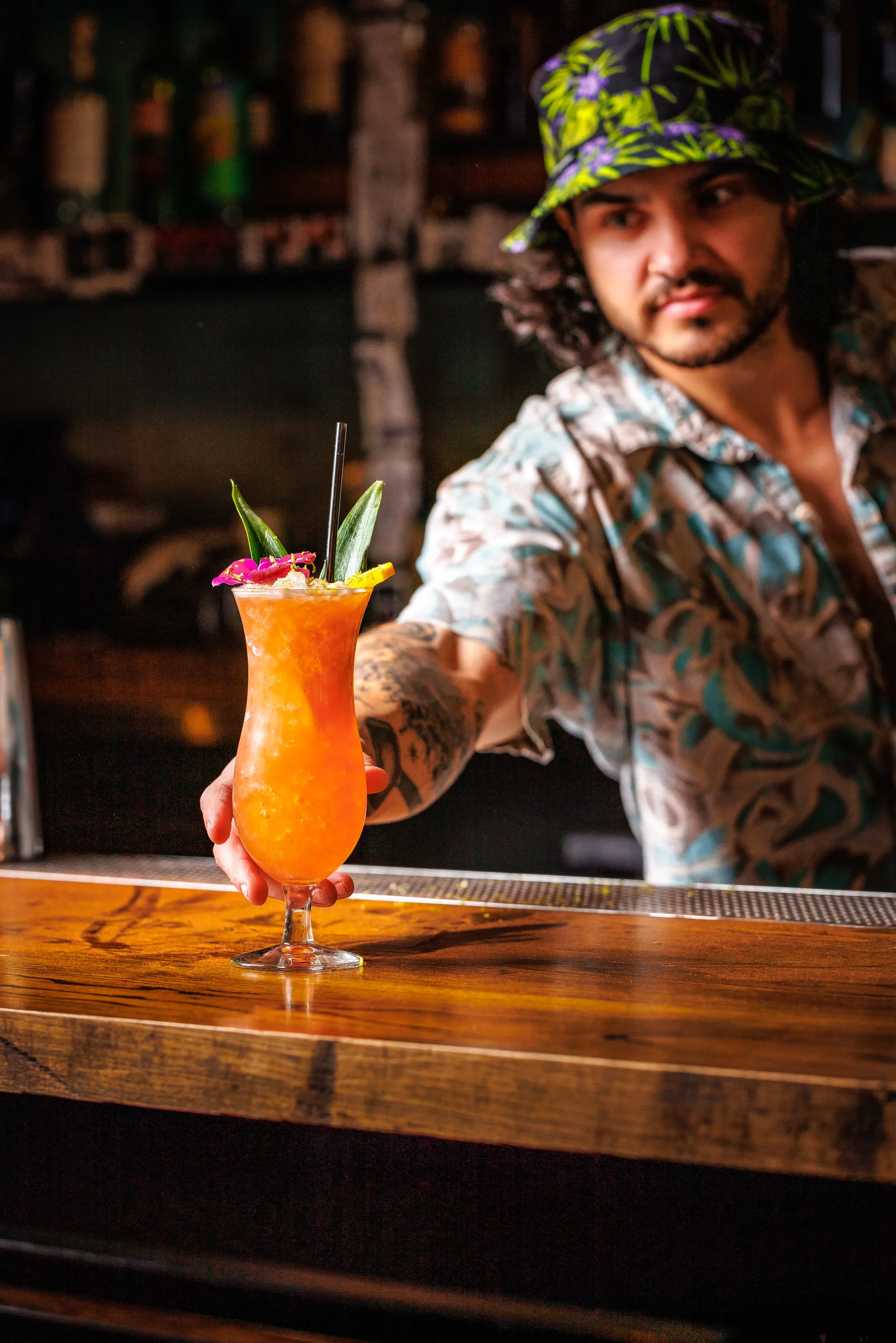Bartender setting down a beautifuil hurricane cocktail