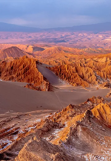 Paisagem desértica do Vale da Lua em San Pedro de Atacama, com formações rochosas e dunas ao entardecer