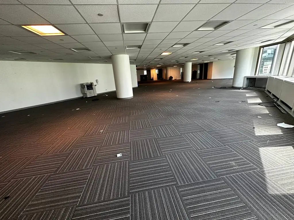 Empty commercial office space with cleaned carpet flooring and cleared area after IT decommissioning and site cleanup