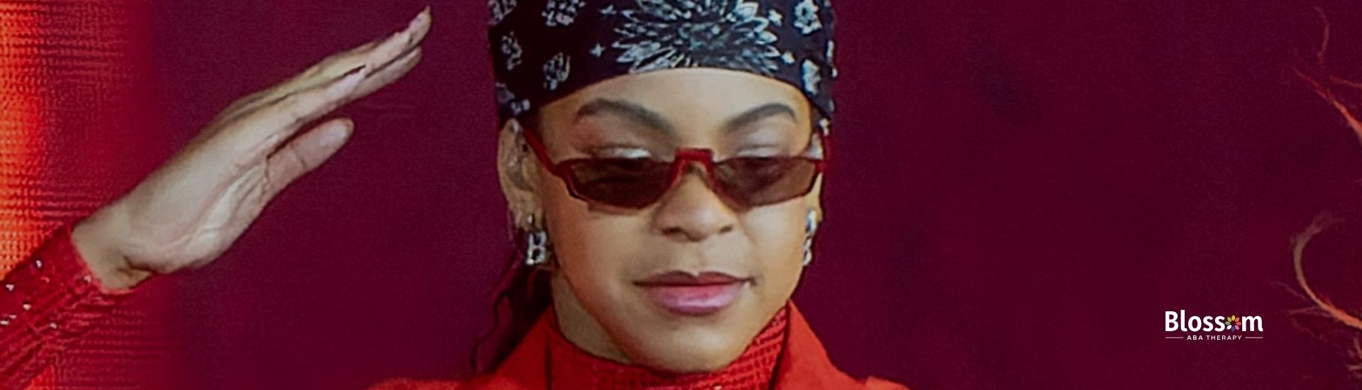 A performer dancing on stage in a red outfit with sunglasses.