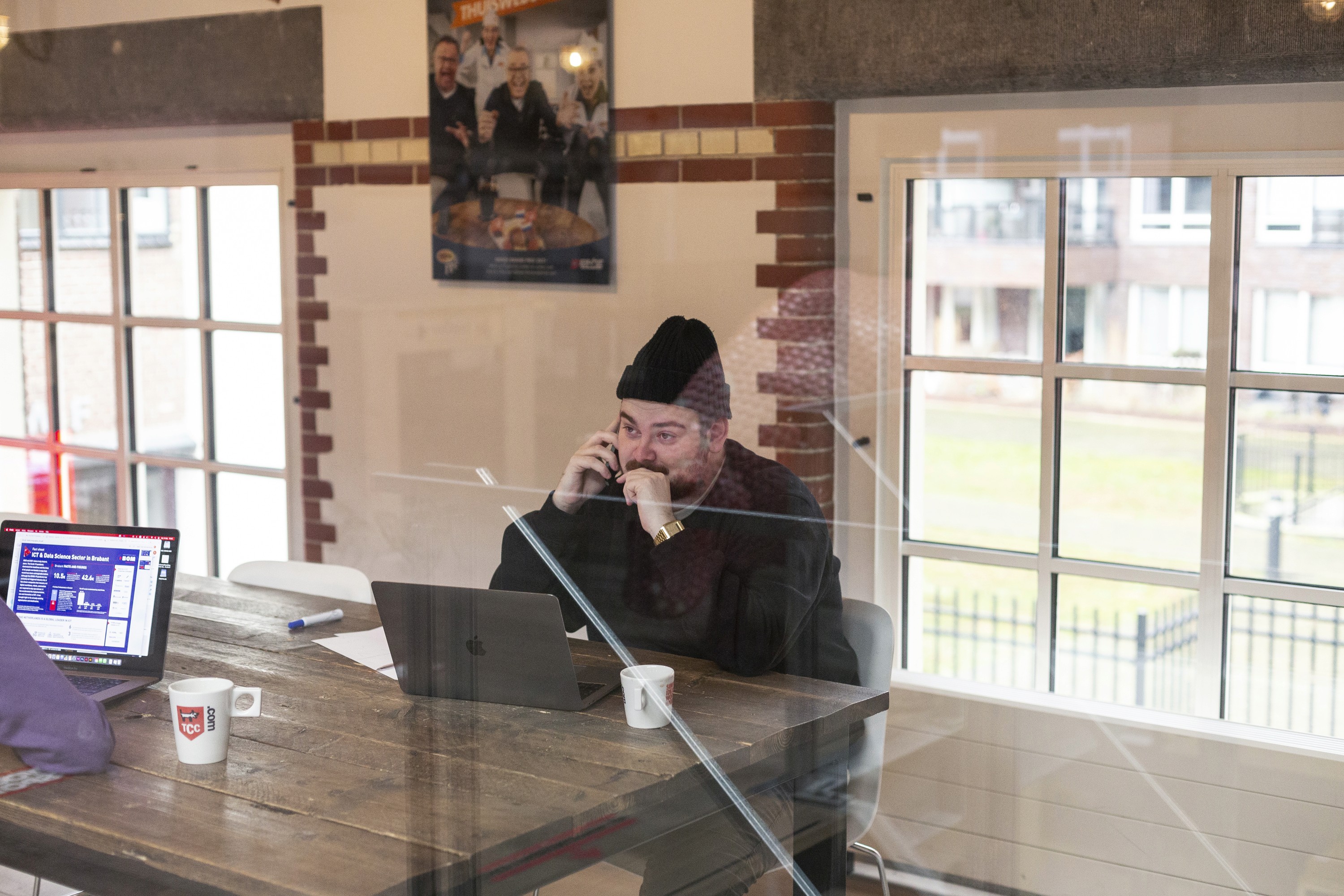 a man with a beanie calling in a meeting room