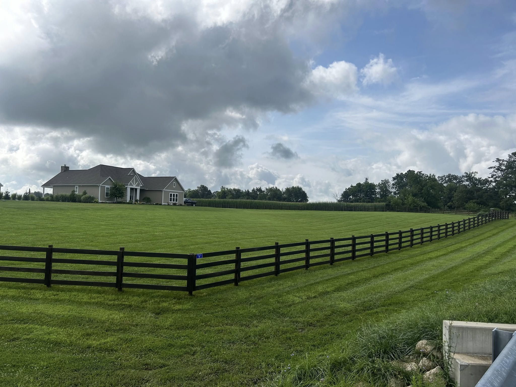 A serene outdoor seating area with two chairs, surrounded by lush greenery and a glassed-in structure.