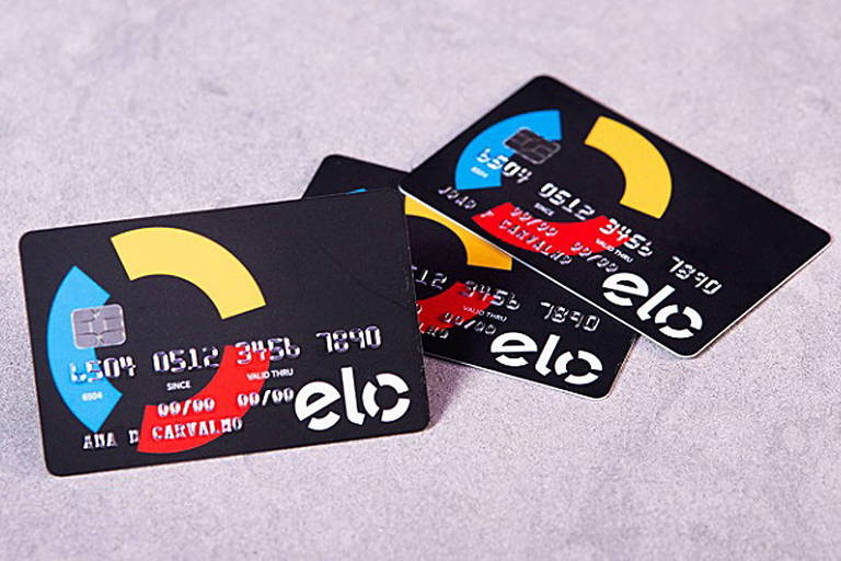 Uma pessoa escrevendo em um caderno sobre uma mesa com uma xícara e outros objetos em um ambiente profissional.