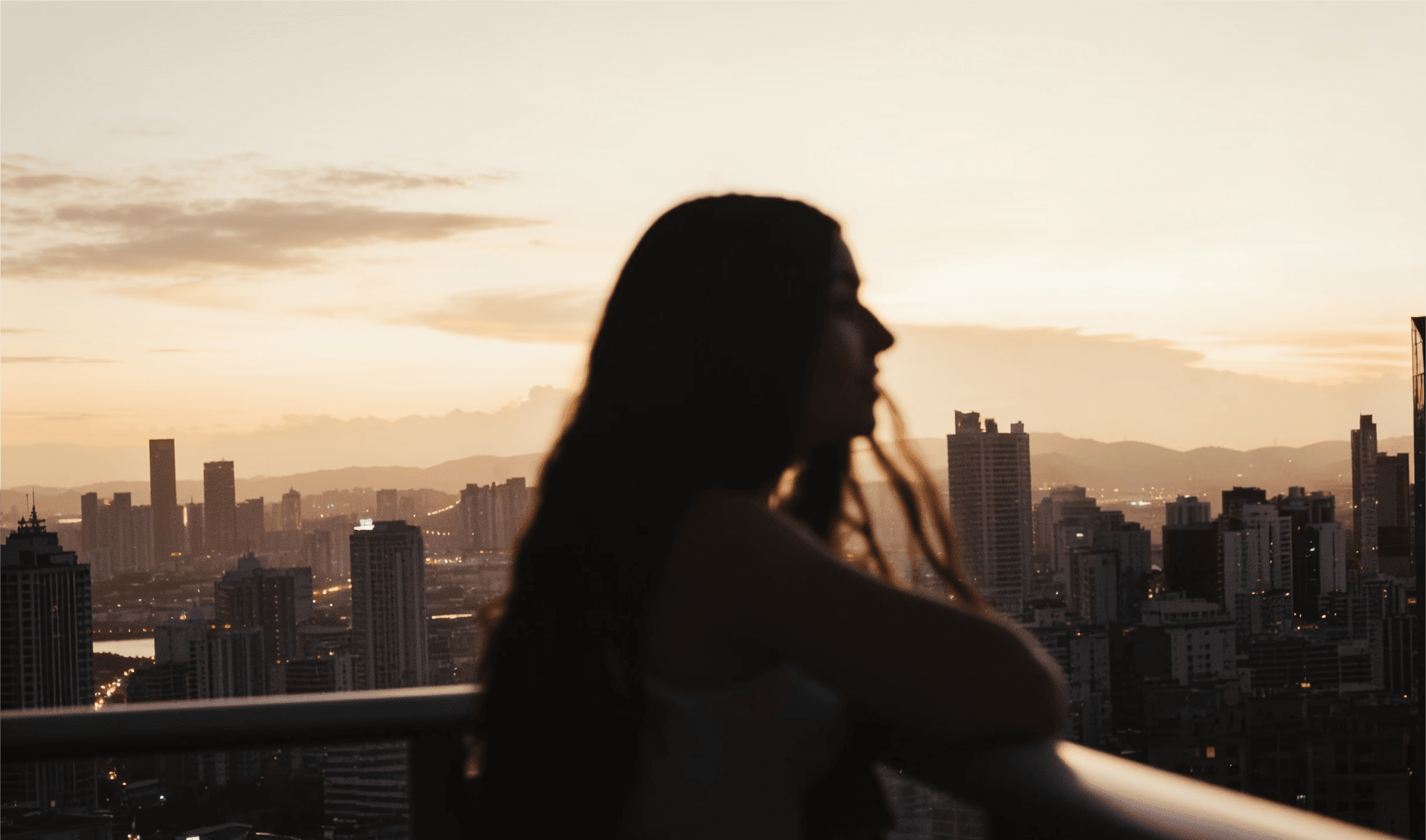 Frauensilhouette vor Stadtpanorama bei Sonnenuntergang – Dreambooster Nutzerin