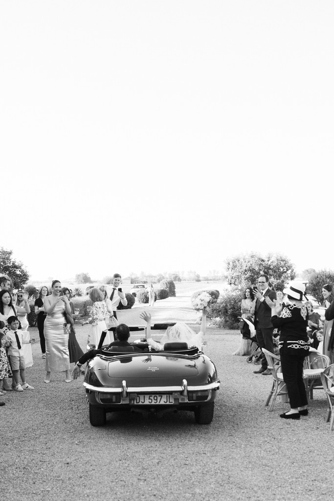 Sposi in auto d'epoca con gli invitati al ricevimento, reportage di matrimonio in villa