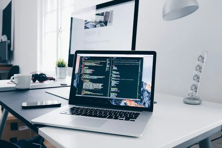Laptop displaying website code on a desk.