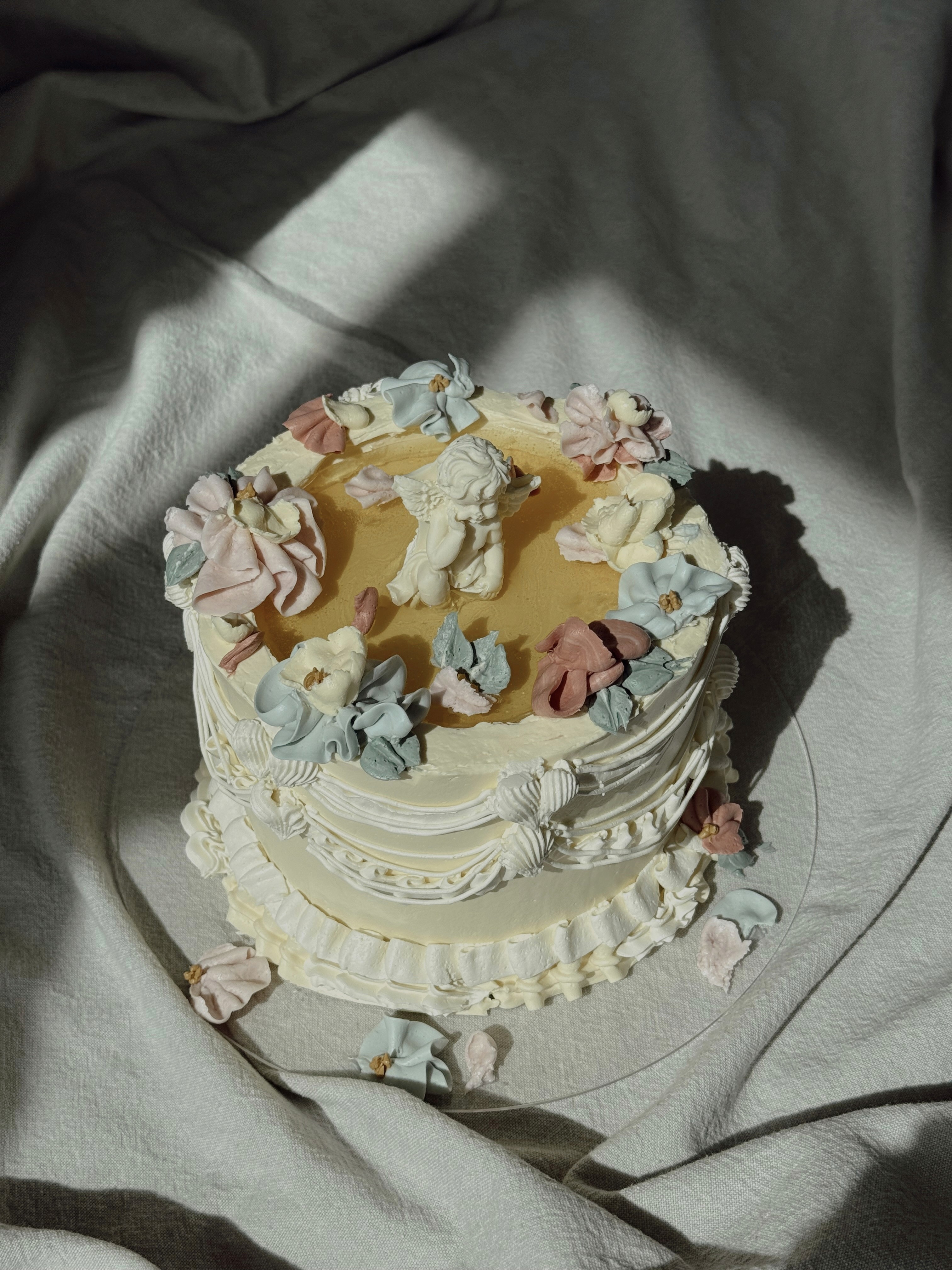 Cream-colored buttercream cake decorated with pastel floral piping