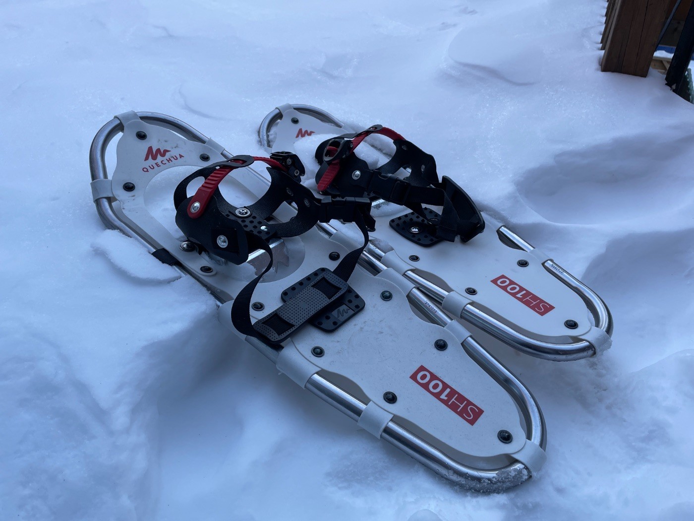 Raquettes à neige Quechua SH100 blanches avec fixation noire et rouge, posées sur la neige fraîche à Montréal.