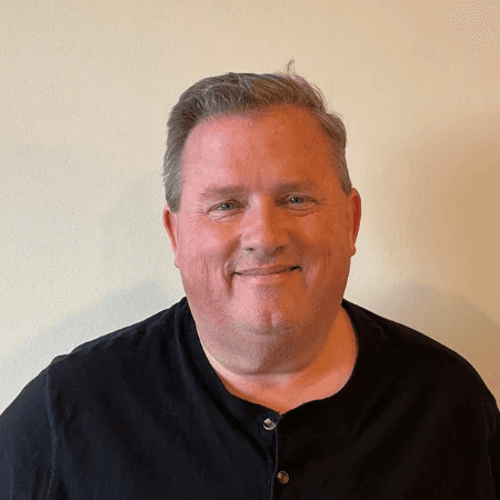 A headshot of a smiling client against an office wall.