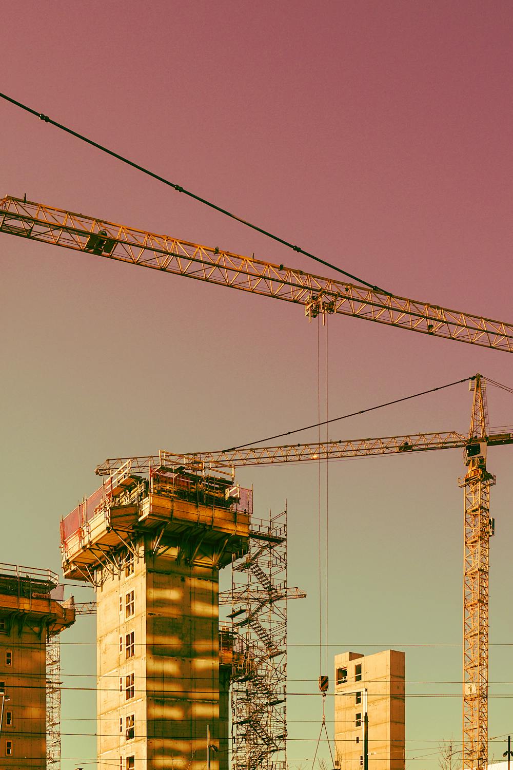 photo taken from below, showing a typical reddish sunset sky with yellow towers and cranes