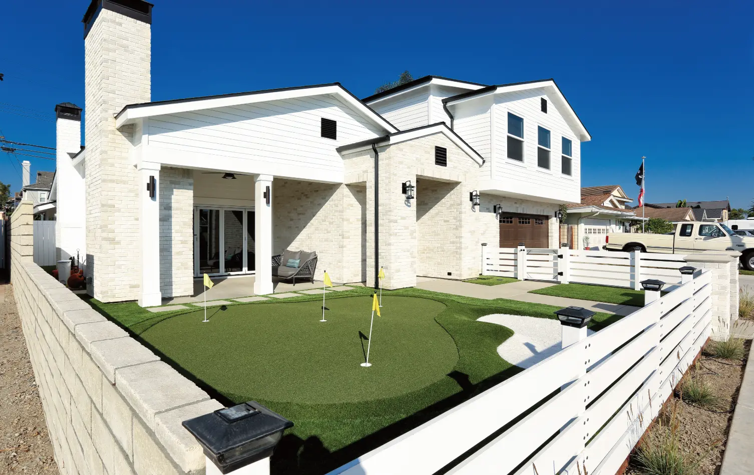 Angled view of American Farmhouse home with font yard putting green. Photo by Chris Darnall.