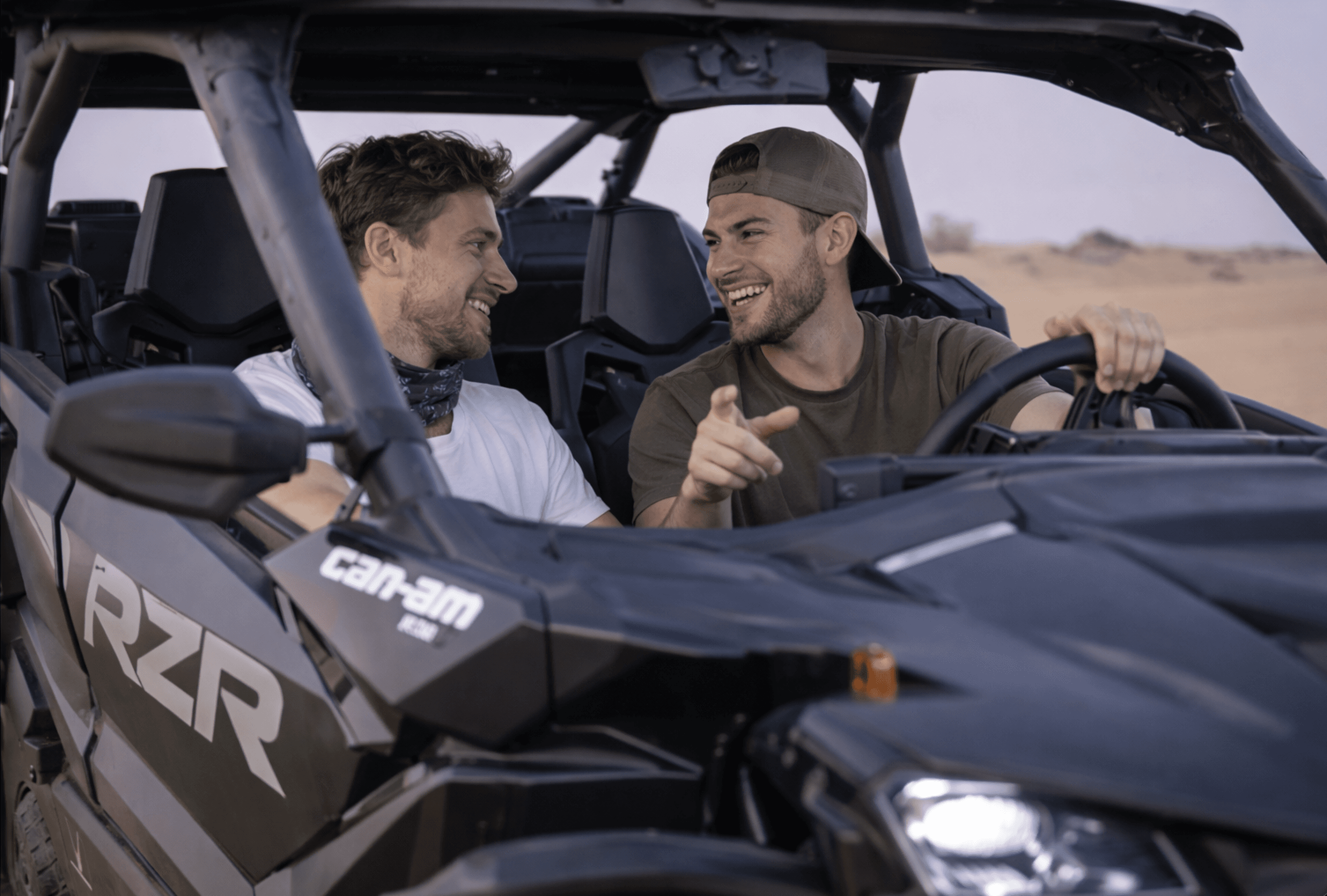 Two guests riding a Polaris RZR 2-seat dune buggy with Dune Quest Tours on a buggy rental Dubai desert tour.