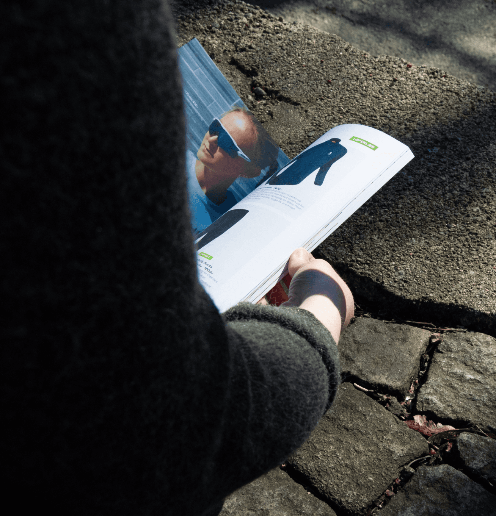 A person holding a magazine outside flipping through the pages in the sun. 