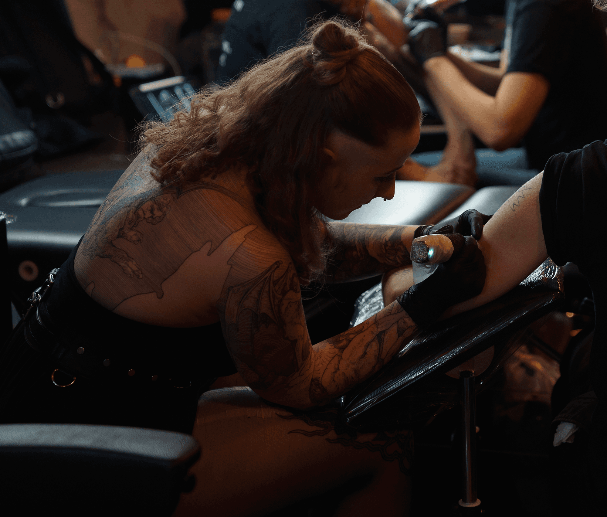Looking over the shoulder of an artist tattooing an arm