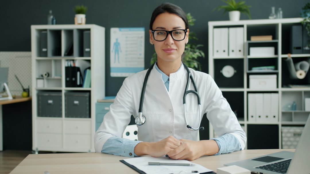 a clean clinical office where a manager is looking at a large wall-mounted monitor displaying a real-time risk heatmap and safety dashboard, cinematic blue and white lighting