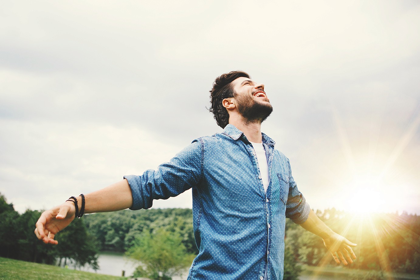 Man met uitgesterkte armen in de natuur, genietend van vrijheid en positieve energie.