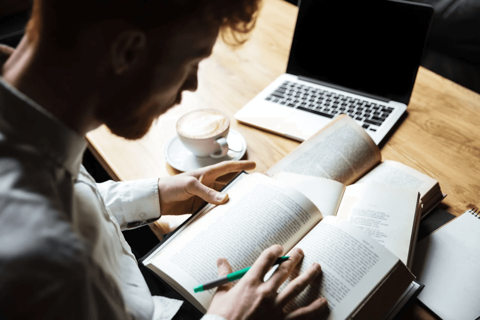 Student reading books while researching online - AI Tools for Systematic Literature Review